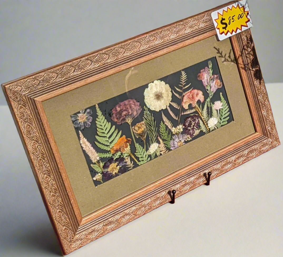 Pressed flower wall decor in ornate brown frame. Medium