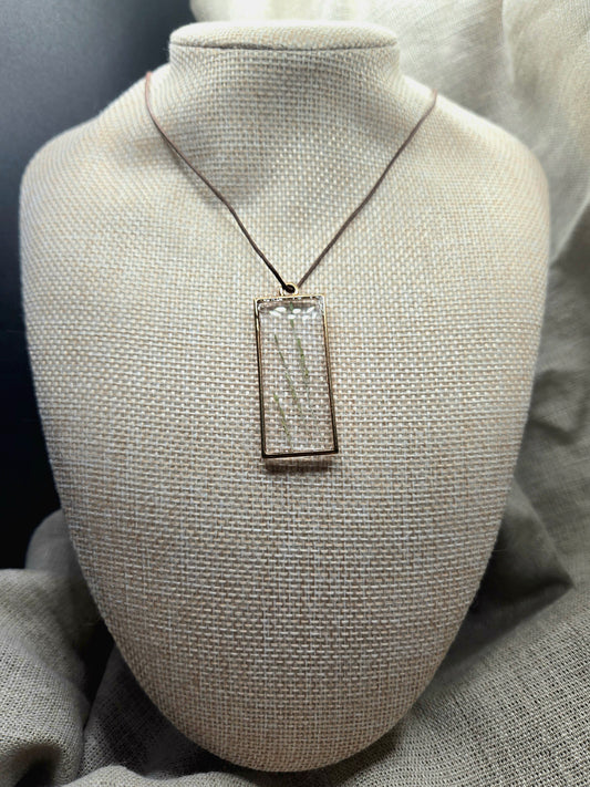 Dainty green leaves in long rectangle pendant on a cord.