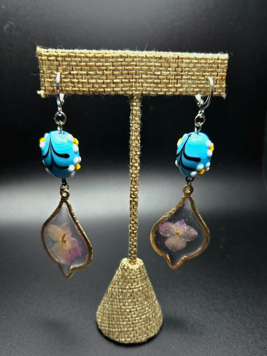 Silver colored dangle earrings with bright glass bead detail.